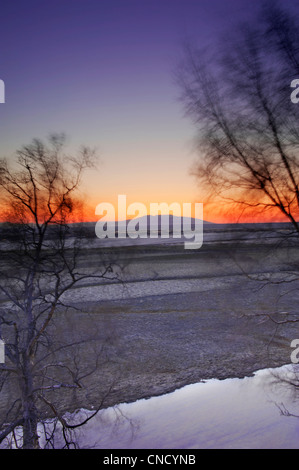 Sun setting behind Mt. Susitna as viewed from the Tony Knowles Coastal Trail in Kincaid Park in Anchorage, Alaska, Winter Stock Photo