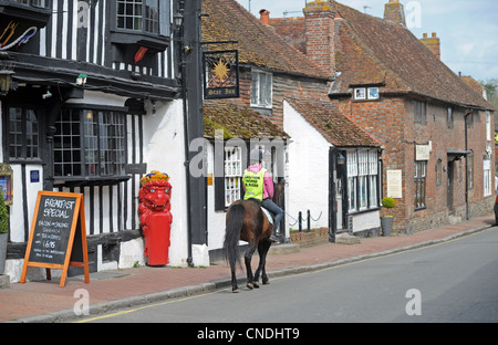 Riding a pony through the small village of Alfriston in East Sussex UK Stock Photo