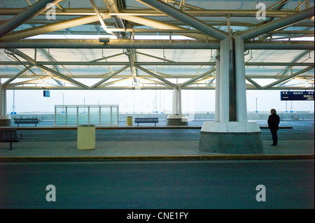 Lone woman waiting for a ride at the terminal at the Denver International Airport, Denver, Colorado, USA Stock Photo