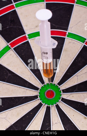 syringe in target on darts board Stock Photo