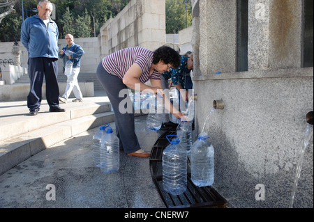 People filling water jugs at a public fountain in Luso, Portugal Stock Photo