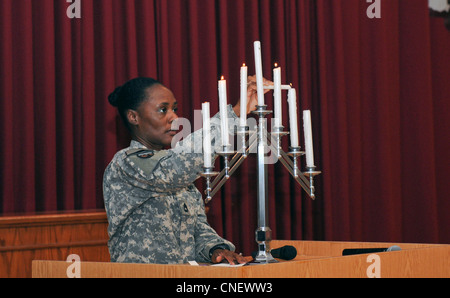 Sgt. 1st Class Shadonika Crawford, section chief for communications and electronics, 420th Movement Control Battalion and Los Angeles native, lights candles as a way to honor victims of the Holocaust during the 2012 Holocaust Remembrance Day Observance held at the Zone 1 Chapel here April 12. During the observance, soldiers spoke, prayed and held a moment of silence to remember this tragic time in history. Third Army is shaping the future by educating its troops about the past in efforts to prevent such atrocities from happening again. Stock Photo