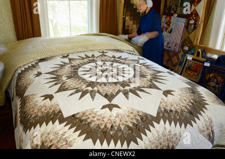 Mennonite seamstress in a bedroom showing handmade quilts near St Jacobs Ontario Canada Stock Photo