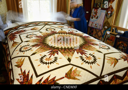 Mennonite seamstress showing handmade quilts in her bedroom near St Jacobs Ontario Stock Photo