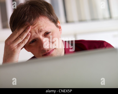 overworked businessman working on laptop computer and having headache. Copy space Stock Photo