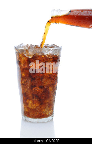 A Bottle of cola soda pouring into a glass filled with ice cubes over a white background with reflection.