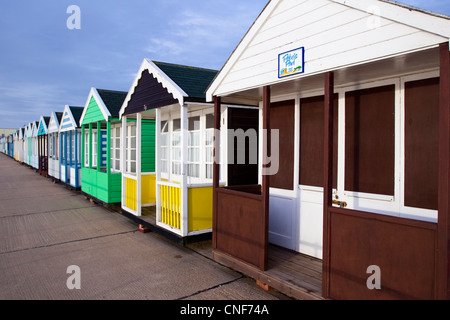 A row of different colored/coloured beach huts receding into the distance from the right to the left of the photo.