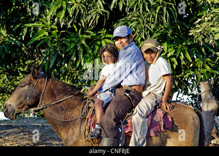 Nicaragua Isla Ometepe Lake Nicaragua happy cowboy family riding horse together after getting cattle back to the farm Stock Photo