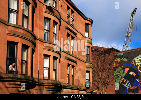 tenement buildings in Howat Street, Govan, Glasgow with the luffing crane of the shipyards in the background Stock Photo
