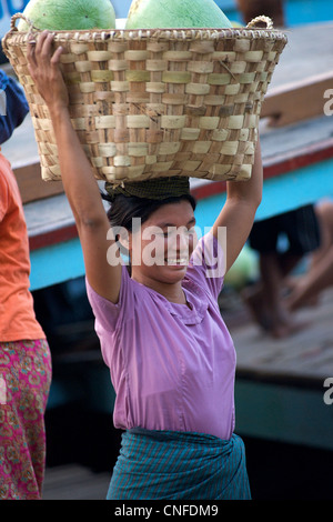 Burmese woman carrying watermelons in a basket off a boat, Mandalay, Burma Stock Photo