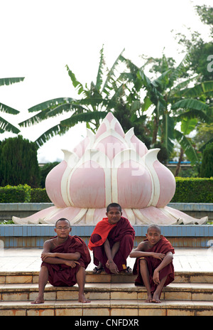 3 buddhist monks sitting on the steps at Mahanthtoo Kanthat Pagoda, Pyin Oo Lwin,  Burma Stock Photo