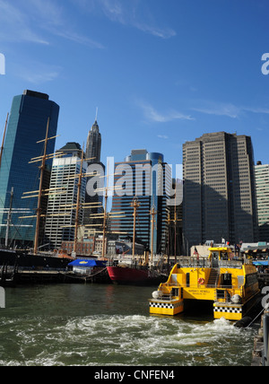 Blue sky portrait, towards Financial District skyscrapers, ships, yellow water taxi, Pier 17, South Street Seaport, New York Stock Photo