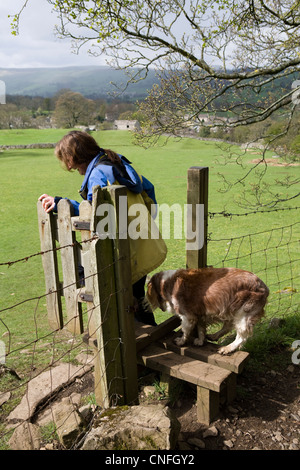 Walkers with dog crossing a Stile in the North Yorkshire National Park, above West Burton, Wensleydale, UK Stock Photo