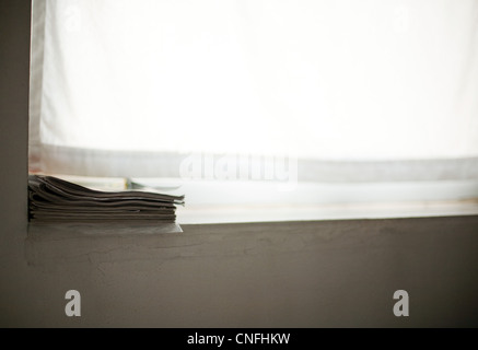 Stack of magazines on windowsill Stock Photo