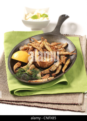 Fried anchovies and potato on cast iron pan Stock Photo