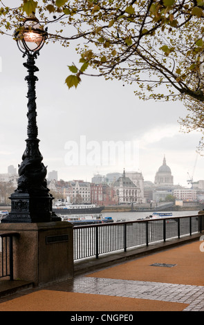Queens Walk, South Bank, London  looking towards St Paul's Cathedral after a Spring shower with lit Victorian light Stock Photo