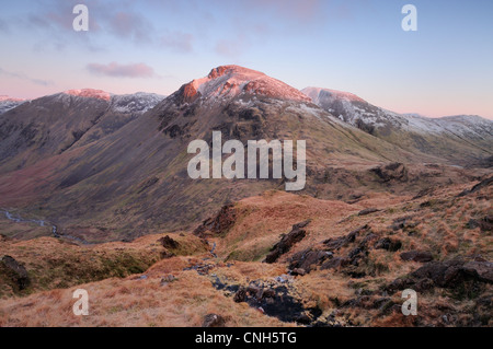 Pink dawn sunlight on Great Gable and Green Gable from the Corridor Route on Scafell Pike. English Lake District mountain view. Stock Photo