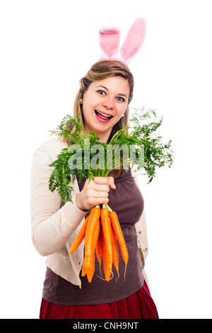 Happy woman in bunny ears with toy carrots on pink background. Easter ...