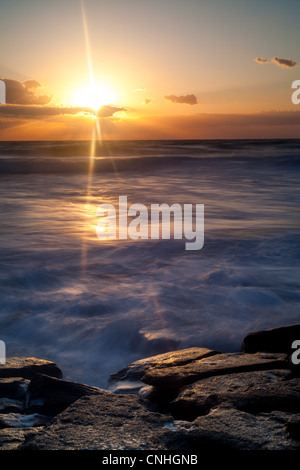 A sunrise image taken at Washington Oaks Gardens State Park in Palm Coast, FL.  This is on the ocean side of the park.  The rock out-cropping in this image is composed of coquina rock, which is a combination of sea shells and sand bonded together with calcite.  This rock has been used for construction in the area for centuries.  Washington Oaks Gardens State Park is located south of St. Augustine in the city of Palm Coast.  The property was once owned by a distant relative of George Washington.  The gardens, located between the coast and the Mantanzas River, were established by Louise and Owen Stock Photo