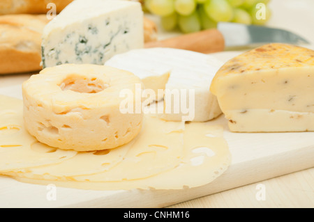 Various Types of Cheese and Grapes on Wooden Chopping Board Stock Photo