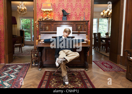 A boy with a cool attitude posing at an old-fashioned upright piano Stock Photo