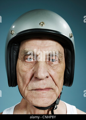 A headshot of a frowning senior man wearing a crash helmet Stock Photo