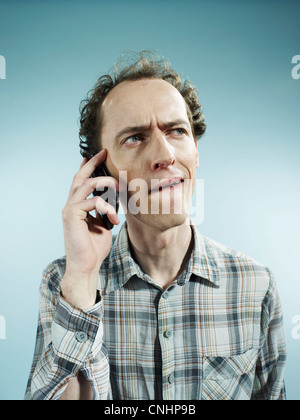 A man using a mobile phone with a confused look on his face Stock Photo