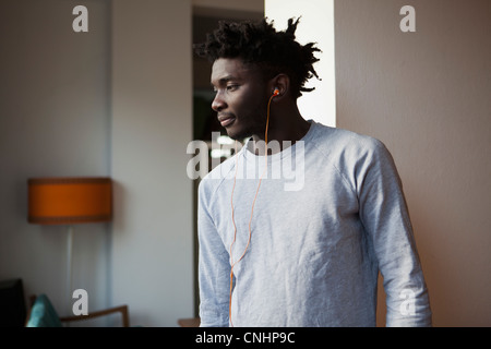 A young man wearing earbuds and looking away Stock Photo