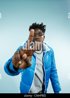 A hip young man flashing the peace sign, focus on hand Stock Photo