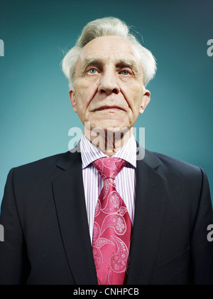 An elegant senior man wearing a suit and bright pink tie Stock Photo