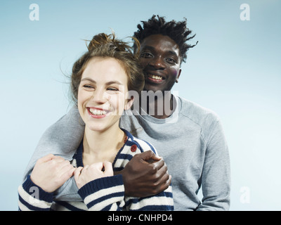 A smiling young man embracing his smiling girlfriend from behind Stock Photo