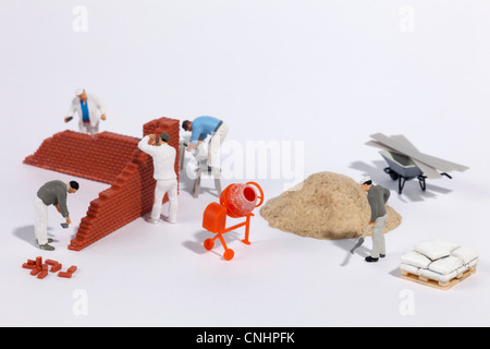 Miniature bricklayers building a brick wall Stock Photo