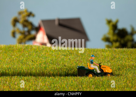 A diorama of a miniature figure using a riding lawnmower Stock Photo