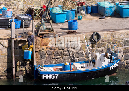 A Cornish crab fisherman on his boat pulls a crab pot/net from the sea ...