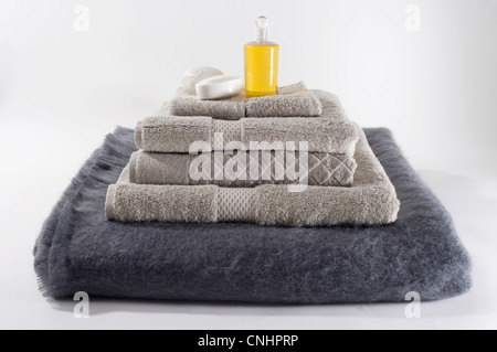 Stacks of folded towels with a bar of soap and massage oil on top Stock Photo