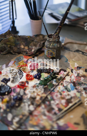 Oil paint on a palette and paintbrushes in a jar Stock Photo