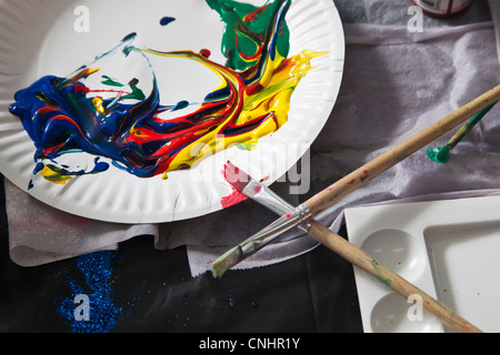 Heaps of acrylic paint on a paper plate and paintbrushes Stock Photo