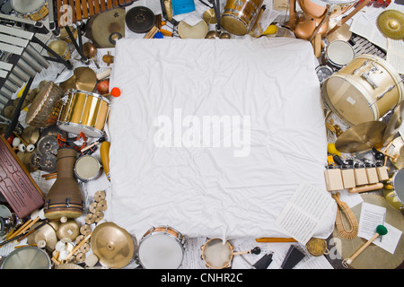 Heaps of various percussion instruments surrounding a white cloth Stock Photo