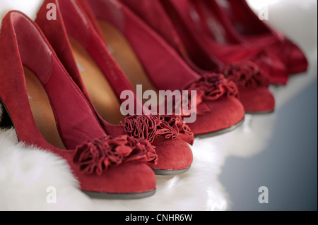 line of red suede bridesmaid womens heeled shoes on a white fur background Stock Photo
