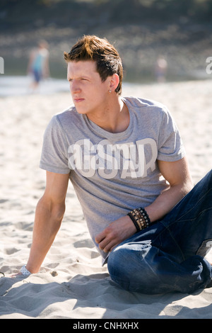 Man sitting on beach looking away from camera. Stock Photo
