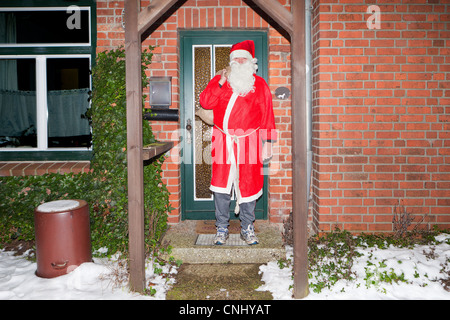 Man dressed as Santa Claus outside house Stock Photo