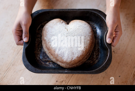 Person holding a tray with heart shaped cake Stock Photo