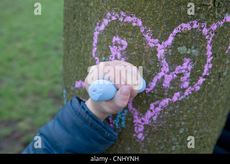 Child drawing heart on a tree trunk Stock Photo