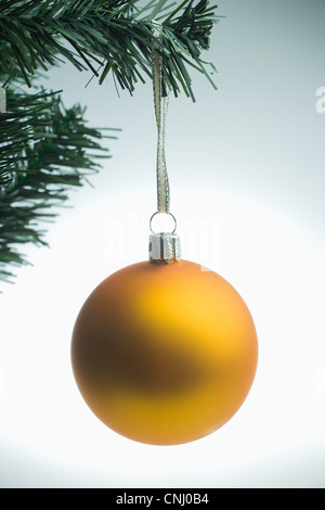 Yellow christmas bauble hanging on tree Stock Photo