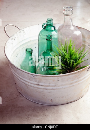 Bottles and plant in an old tub Stock Photo