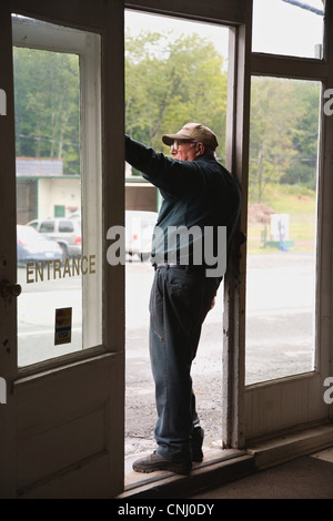 Senior man in doorway of store, looking out Stock Photo