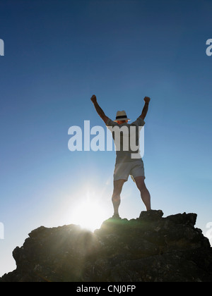 Man standing on top of rock with arms raised Stock Photo