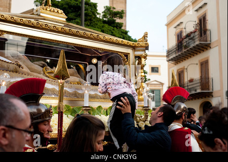 Palermo, Sicily, Italy - Traditional Easter celebrations, a man holding her daughter for her to kiss the statue of Christ. Stock Photo