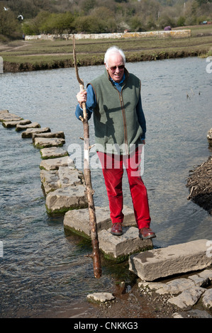 Man crossing stepping stones on the River Ewenny at Ogmore in the Vale of Glamorgan South Wales UK Stock Photo