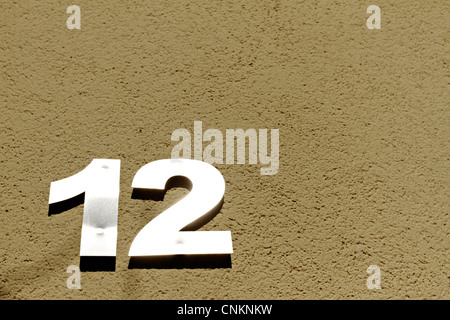 Number 12 on a mustard coloured concrete wall Stock Photo